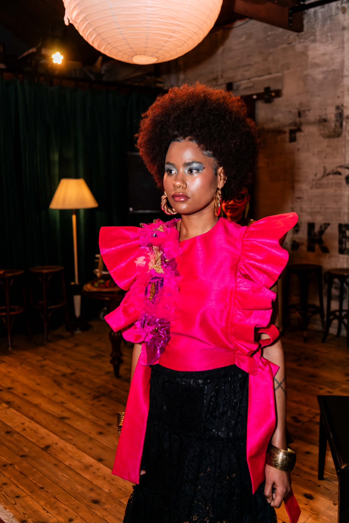 Editorial makeup: icy blue eyeshadow, glossy lip and dewy highlight, model in a pink ruffled top
