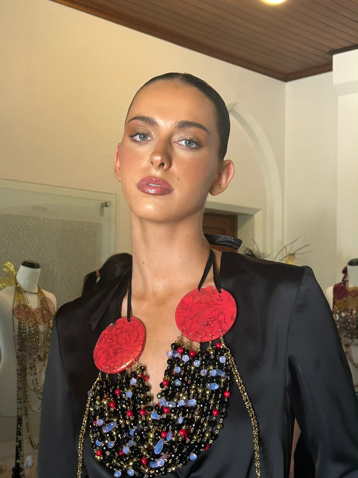 Editorial makeup: bronzed skin, shimmer lid and glossy rose lip, backstage with a statement beaded necklace